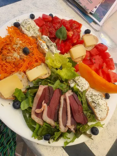 assiette composée avec des crudités, du fromage et des magrets de canard