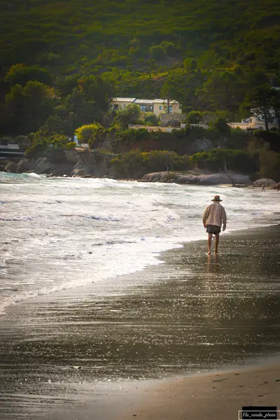 Homme seul avec un chapeau qui marche sur la plage