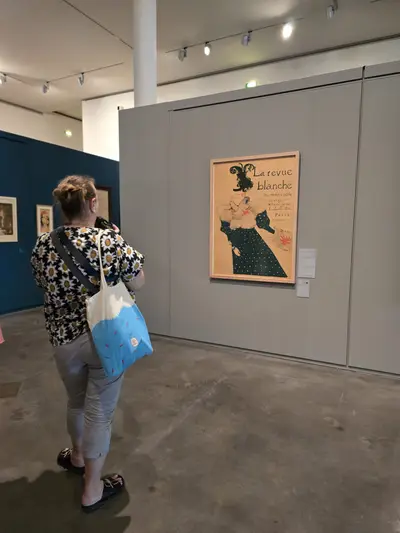 exposition temporaire sur les affiches: visiteuse avec un sac