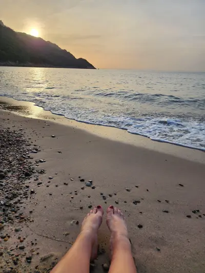 Pieds sur le sable devant le coucher de soleil